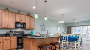 Una cocina con armarios de madera, un microondas negro y una isla central con taburetes.