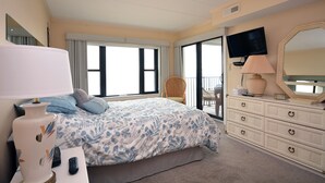 A bedroom with a bed, a dresser, a TV, a lamp, and a chair.