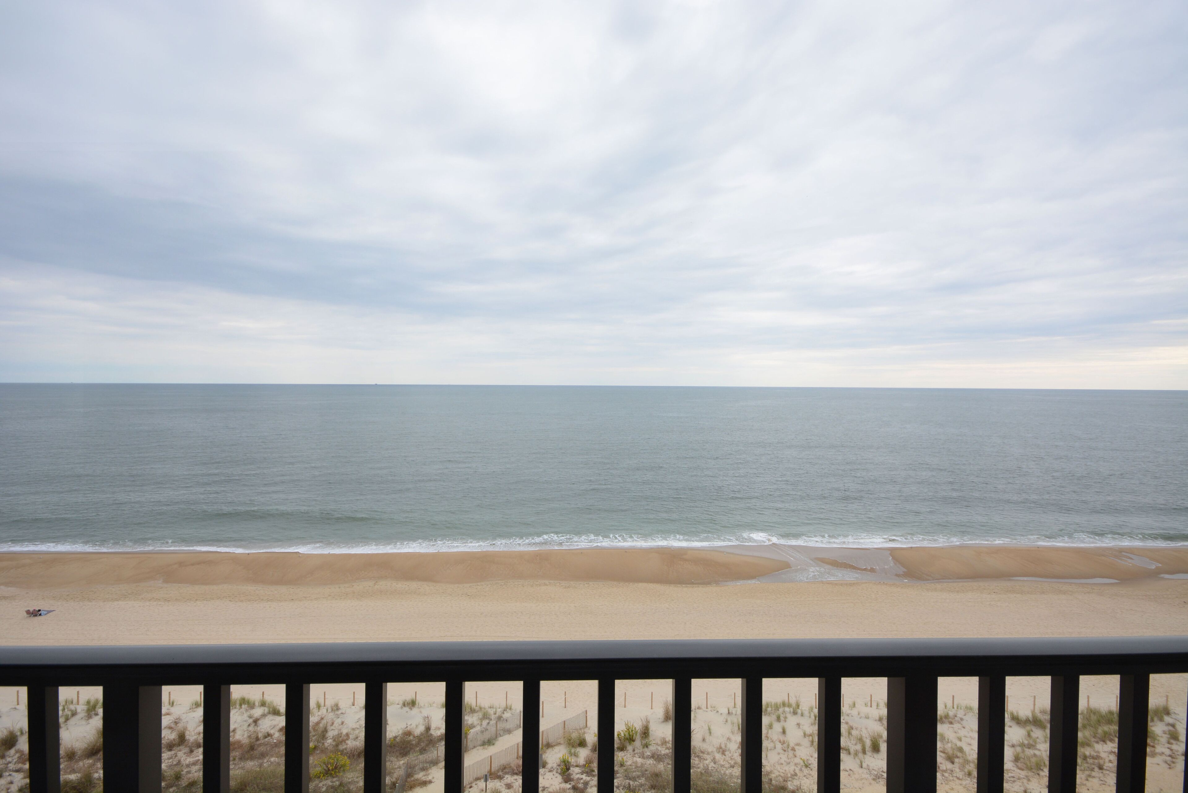 A beach view with a railing in the foreground.