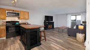 Une cuisine moderne avec des meubles en bois, un four à micro-ondes, une cuisinière et un meuble TV noir.