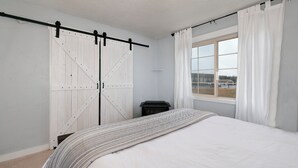 Une chambre à coucher avec un lit, une fenêtre avec des rideaux et une porte coulissante de style grange.