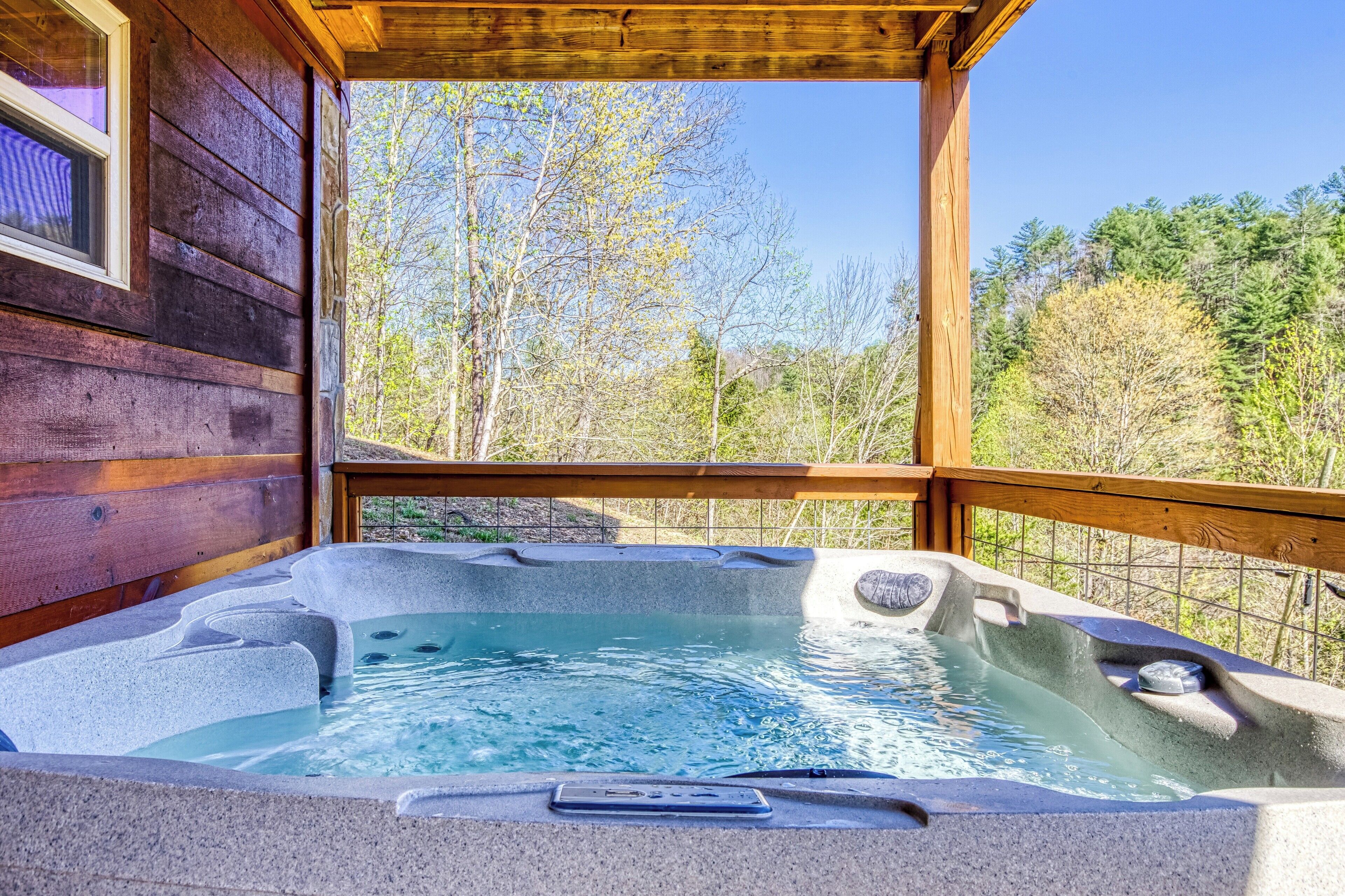Een houten hut met een jacuzzi op een terras.