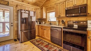 A wooden cabin kitchen with a stainless steel refrigerator, microwave, oven, and dishwasher. - Sunshine Ridge, Hot Tub, Game Room, $560 FREE tickets each paid day (Sevierville)