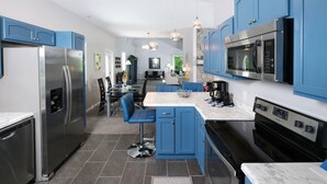 Una cocina moderna con armarios azules, electrodomésticos de acero inoxidable y una encimera de mármol.