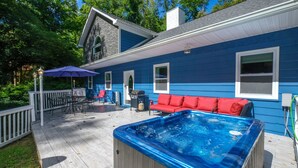 Una terraza con hidromasaje, mobiliario exterior y una casa azul.