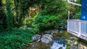 Un puente de piedra sobre un arroyo cristalino, con abundante vegetación a ambos lados.