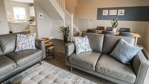 Ein modernes Wohnzimmer mit einem grauen Sofagarnitur, einem Couchtisch und einem gemusterten Teppich.