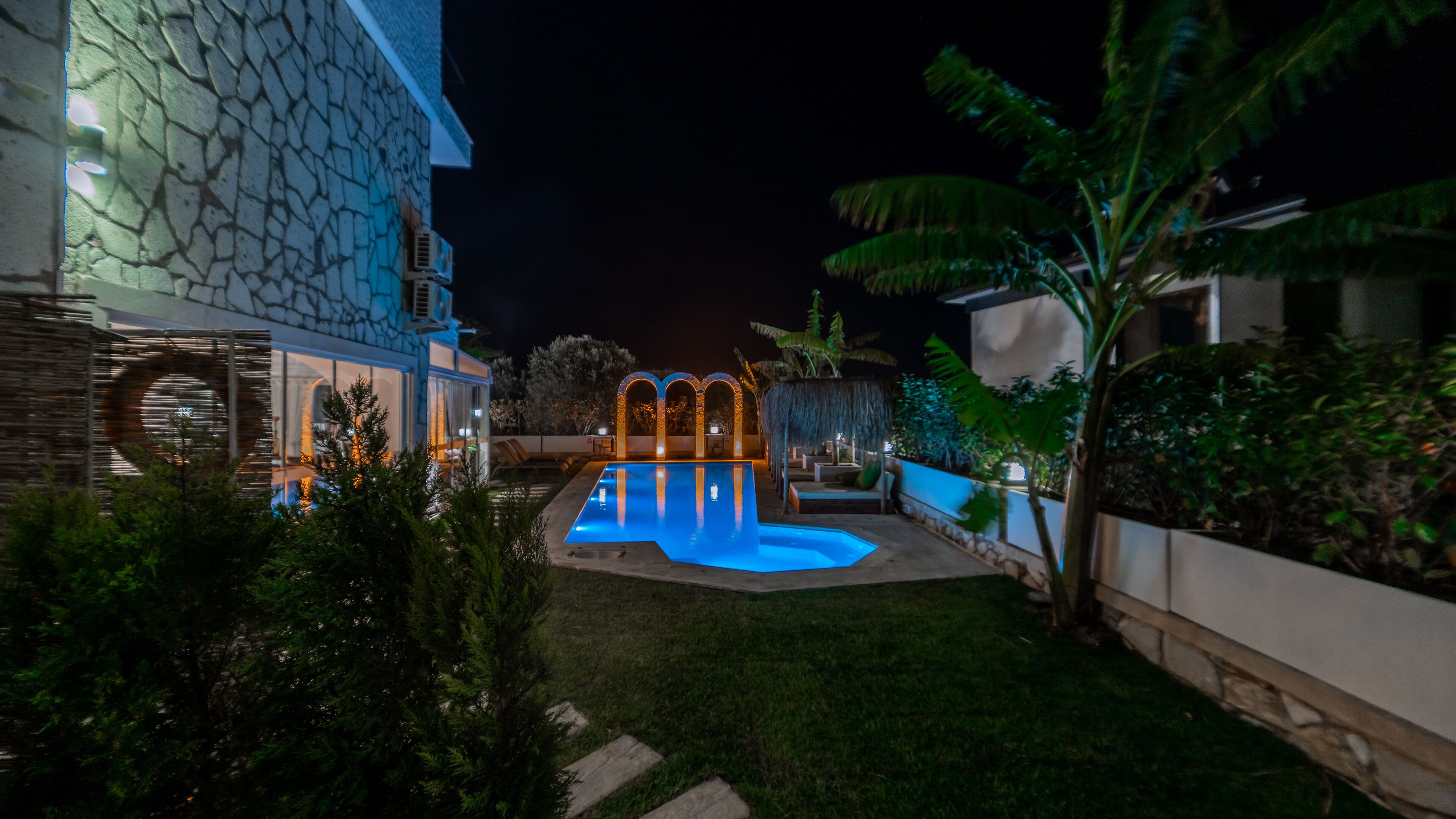A modern building with a stone facade, a swimming pool, and well-maintained landscaping.