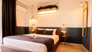 Una habitación de hotel moderna con una cama grande, mesitas de noche, un espejo y una planta en la pared.