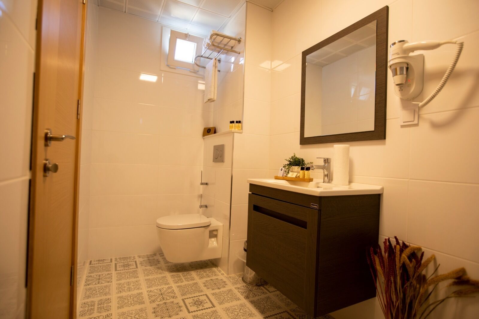 A bathroom with a toilet, a sink with a mirror, and a shower area.