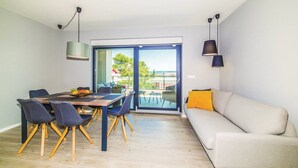 A modern living room with a dining area, large sliding glass doors leading to a balcony, and a sofa with a yellow pillow. - Luxury Dream House in Kaštel Novi (Kaštel Novi)