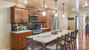 A kitchen with wooden cabinets, a stainless steel refrigerator, a microwave, and a granite countertop.