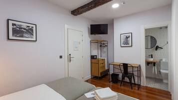 A bedroom with a bed, a desk, and a chair. There is a bathroom with a toilet and sink.