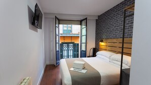 A hotel room with a bed, a TV, a radiator, and a view of the outside balcony. - Casual Bilbao Mardones (Bilbao)