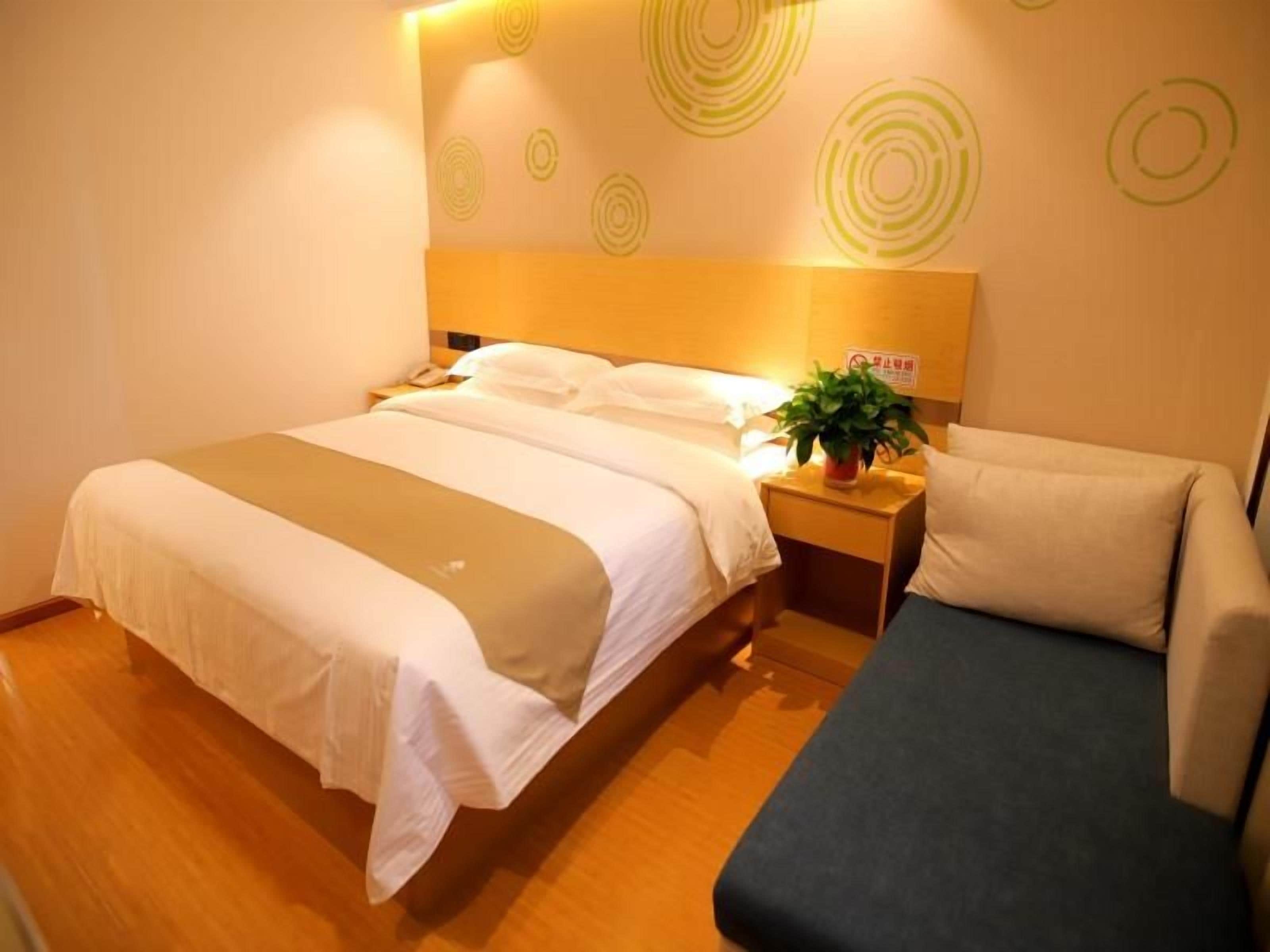 A hotel room with a bed, bedside table, and a sofa.
