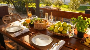 An outdoor dining table set with plates, cutlery, glasses, and a basket of apples. - Villa Sunčica ZadarVillas (Sukošan)
