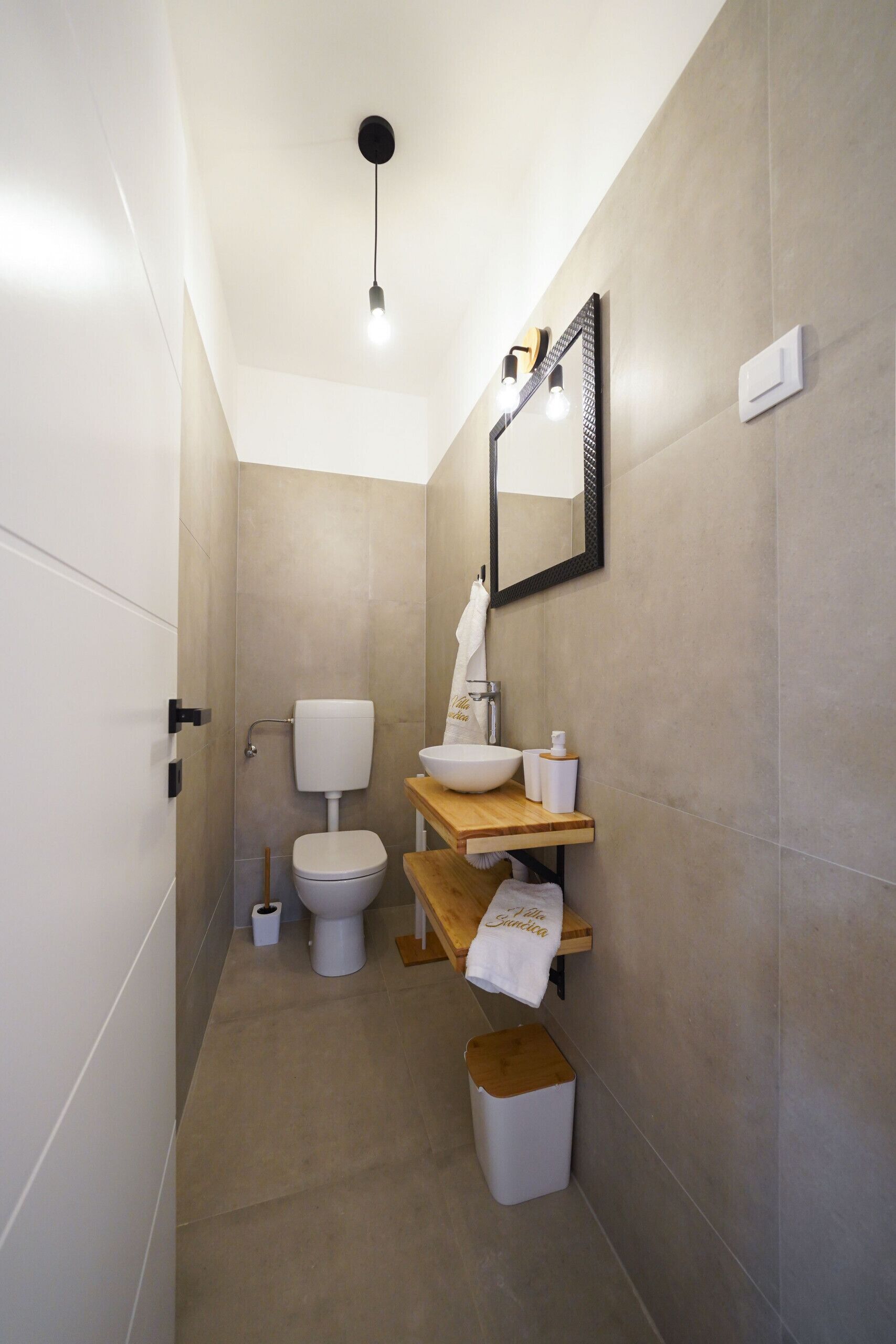 A compact bathroom with a toilet, sink, and mirror.