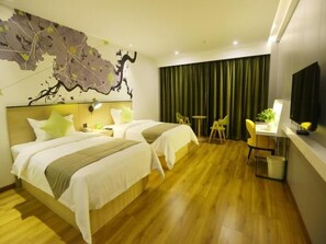 Ein Hotelzimmer mit zwei Betten, einem Schreibtisch, einem Stuhl, einem Fernseher und einer Karte an der Wand.