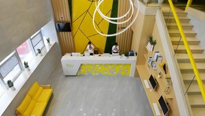 A modern reception desk with a yellow and white color scheme, a staircase with yellow railings, and a yellow sofa in the lobby area. - Vatica Huanggang Luotian County City Square Hotel (Huanggang)