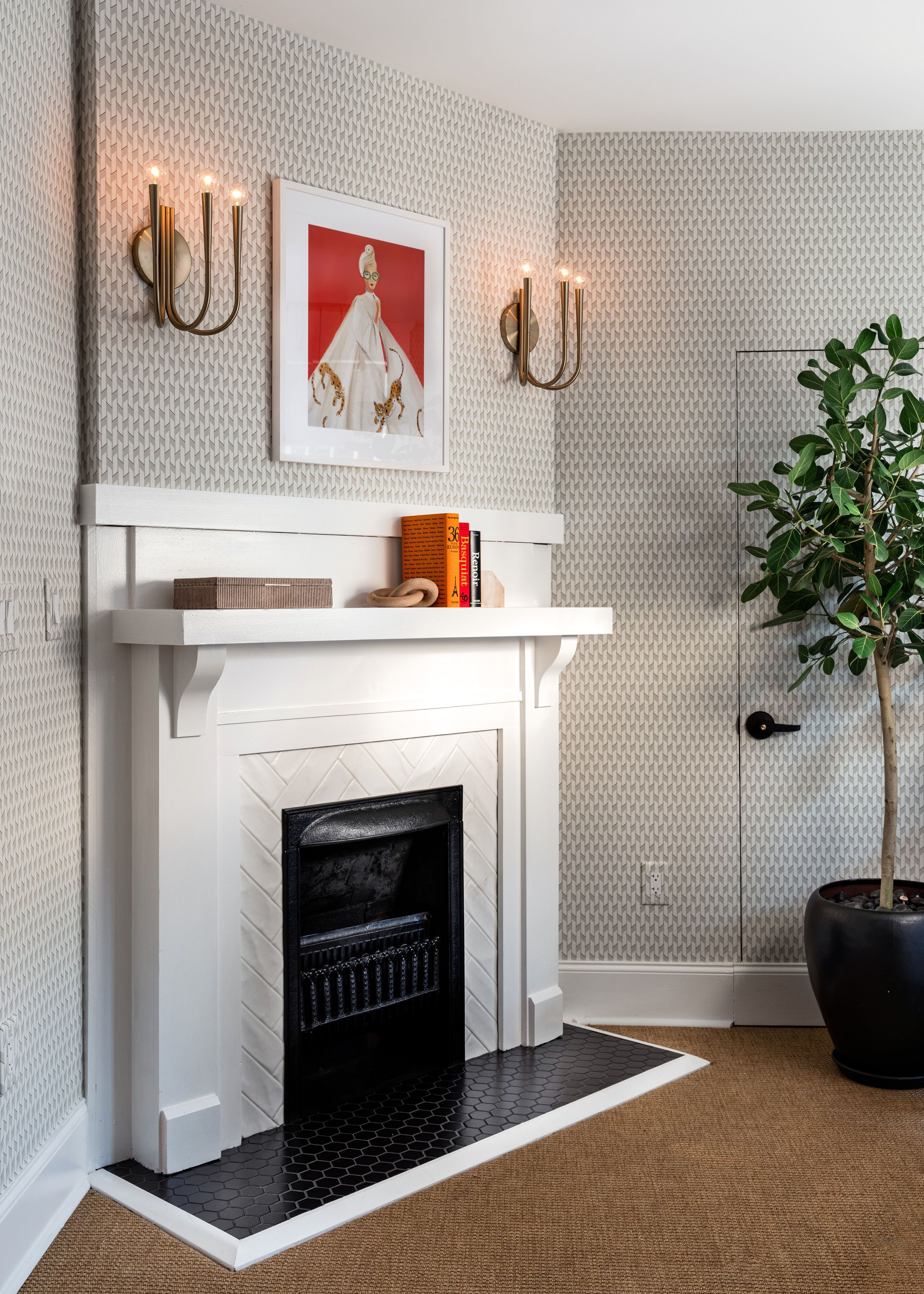 A modern living room with a white fireplace, a framed artwork above it, and a potted plant to the right.