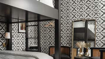A modern hotel room with a bunk bed, a wooden side table with a vase, a chair, and a mirror.