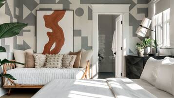 Une chambre à coucher avec un lit, une table de chevet, une lampe et un grand tableau abstrait accroché au mur.