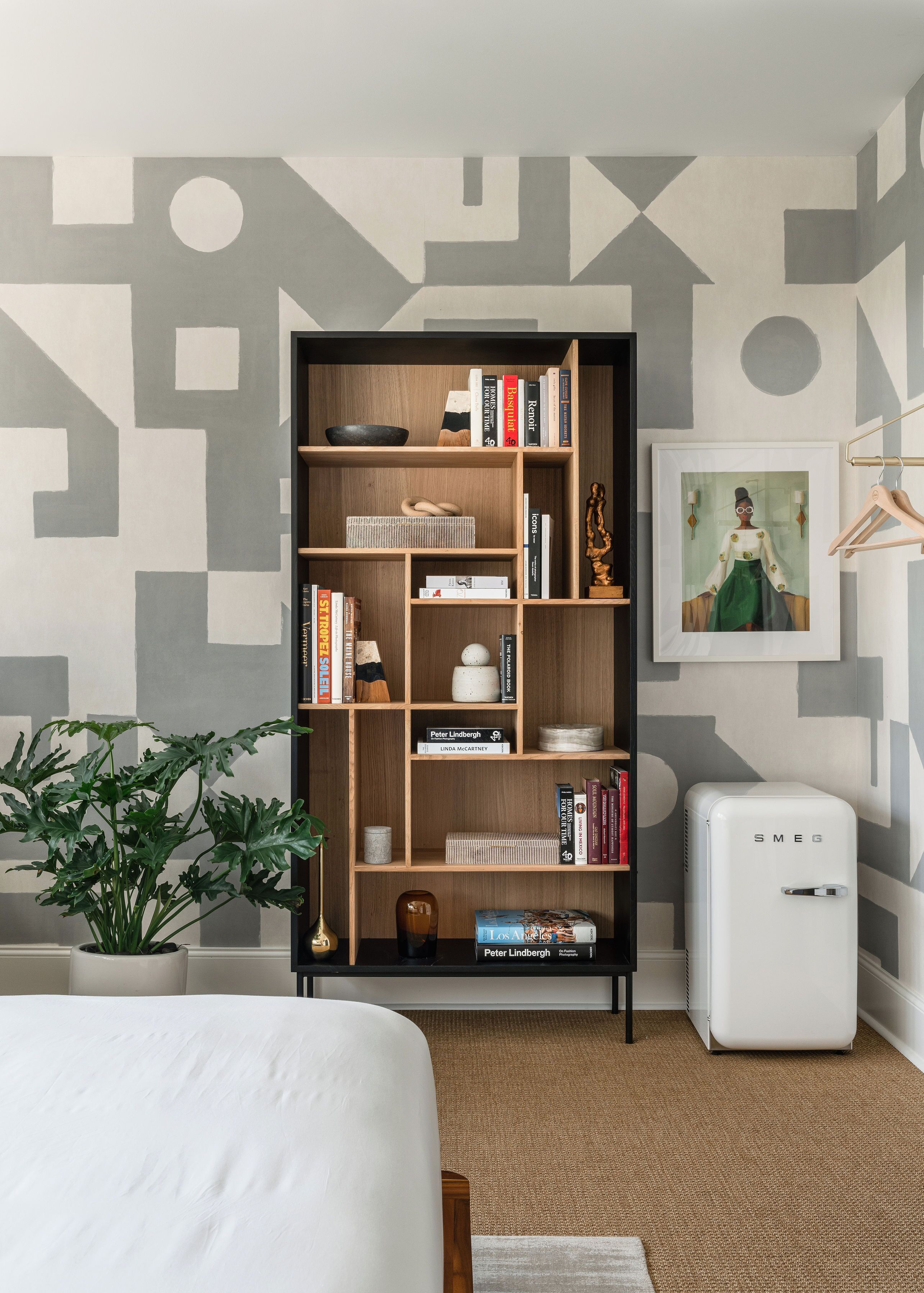 A modern room with a wooden bookshelf, a small white appliance, and a potted plant.