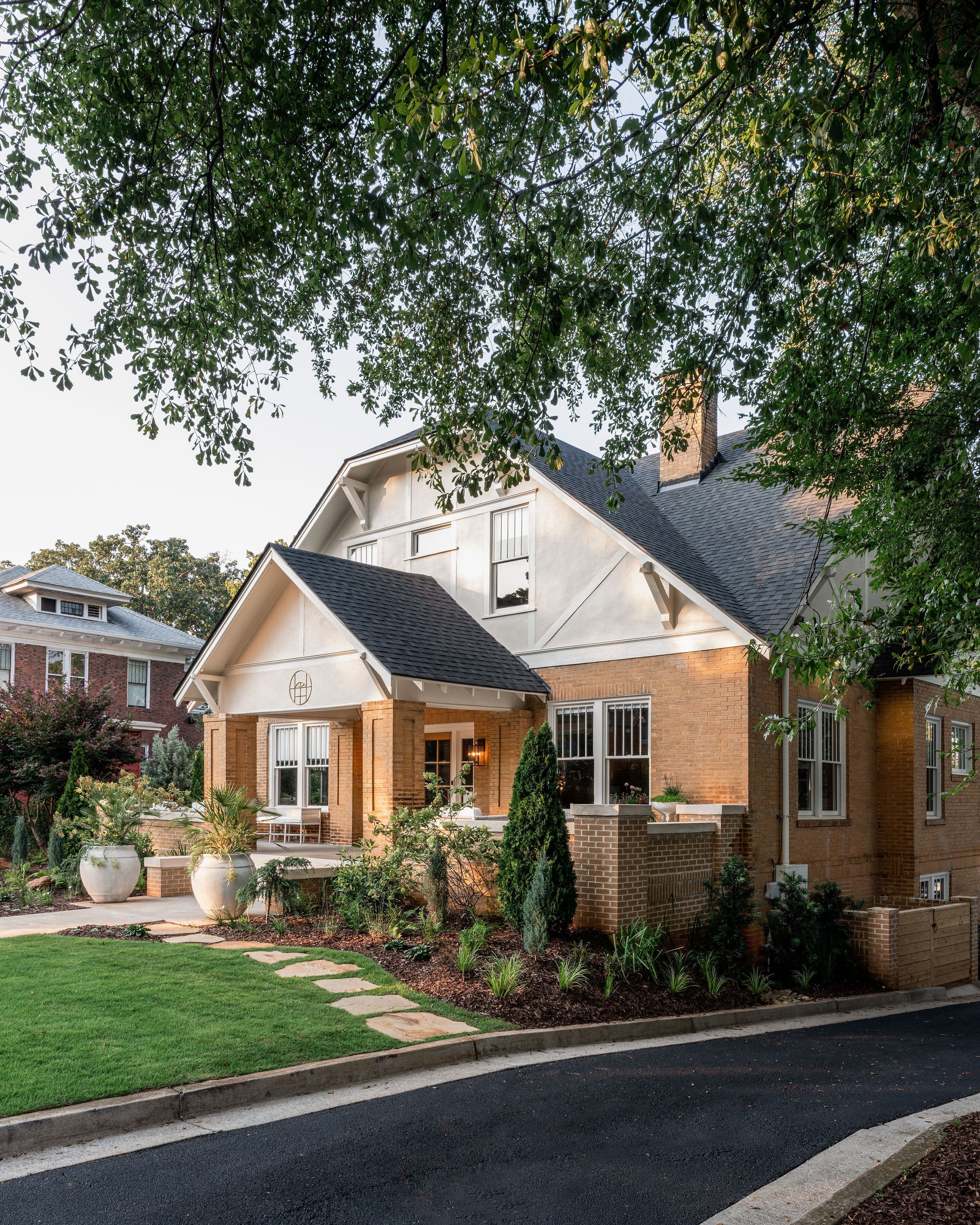 A two-story house with a brick exterior, a covered front porch, and a well-maintained garden.