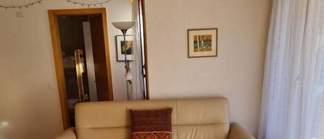 Un salon avec un canapé beige, une table basse en bois et un banc.