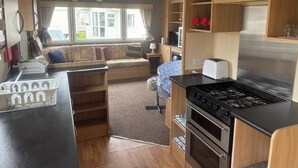A compact RV kitchen with a stove, oven, and a dining area with a bench.