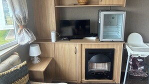 A compact living space with a TV, refrigerator, and a Star Wars-themed chair.