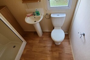 A small bathroom with a toilet, sink, and a window above the sink. - Family Friendly - Sleeps4 - Close To Nature (Rhyl)