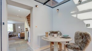 Un comedor acogedor con una mesa redonda, un sillón de piel y vistas a una escalera que lleva a otra habitación.