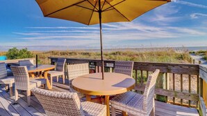 A deck with wicker furniture and a yellow umbrella, overlooking a beach. - 2112 SeaCrest -Stunning Villa offers Lowcountry luxury living! (Hilton Head Island)