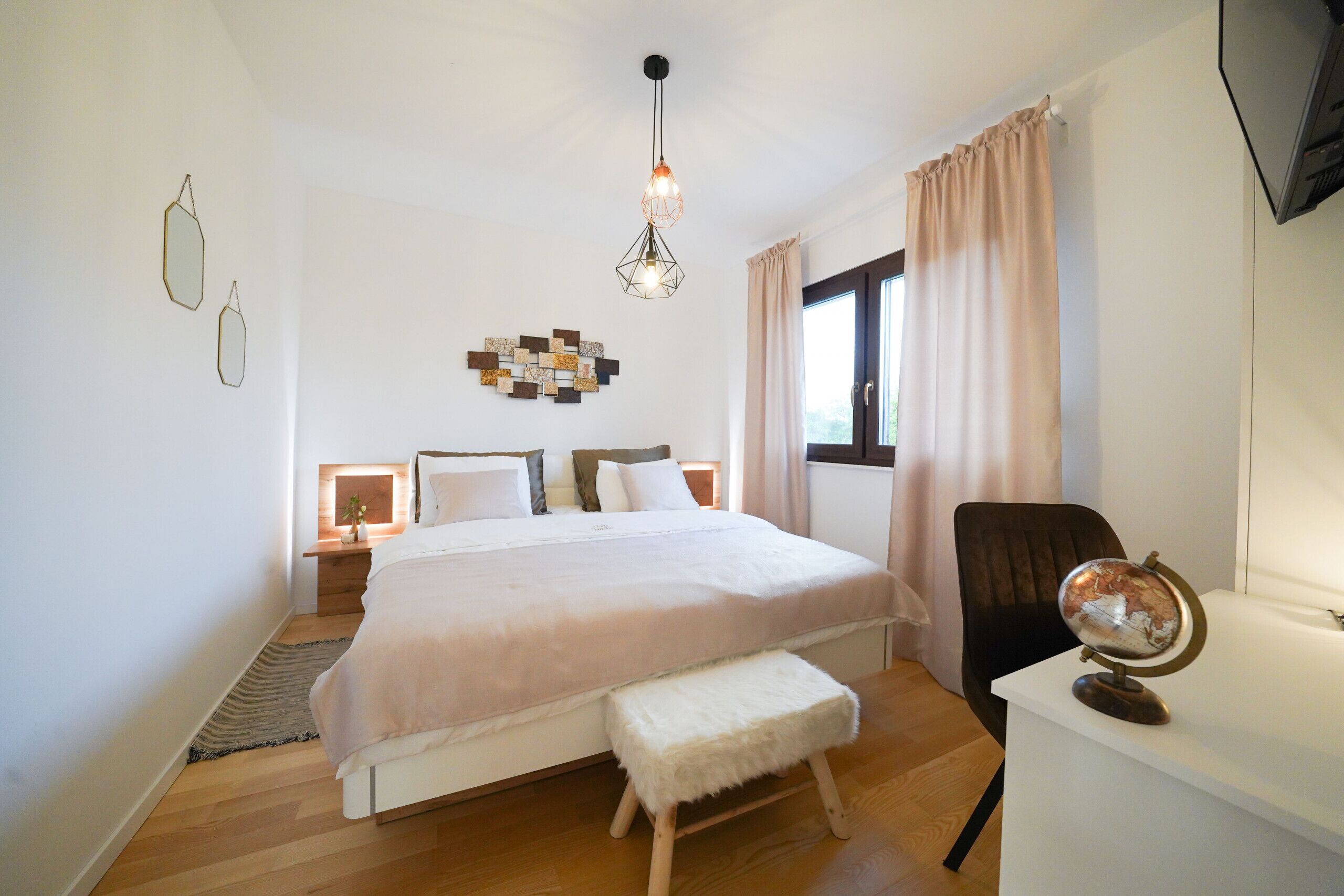 A bedroom with a bed, bedside tables, a globe, and a window with curtains.