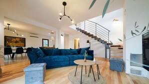 Una sala de estar moderna con un sofá azul, una mesa de centro redonda y una escalera.