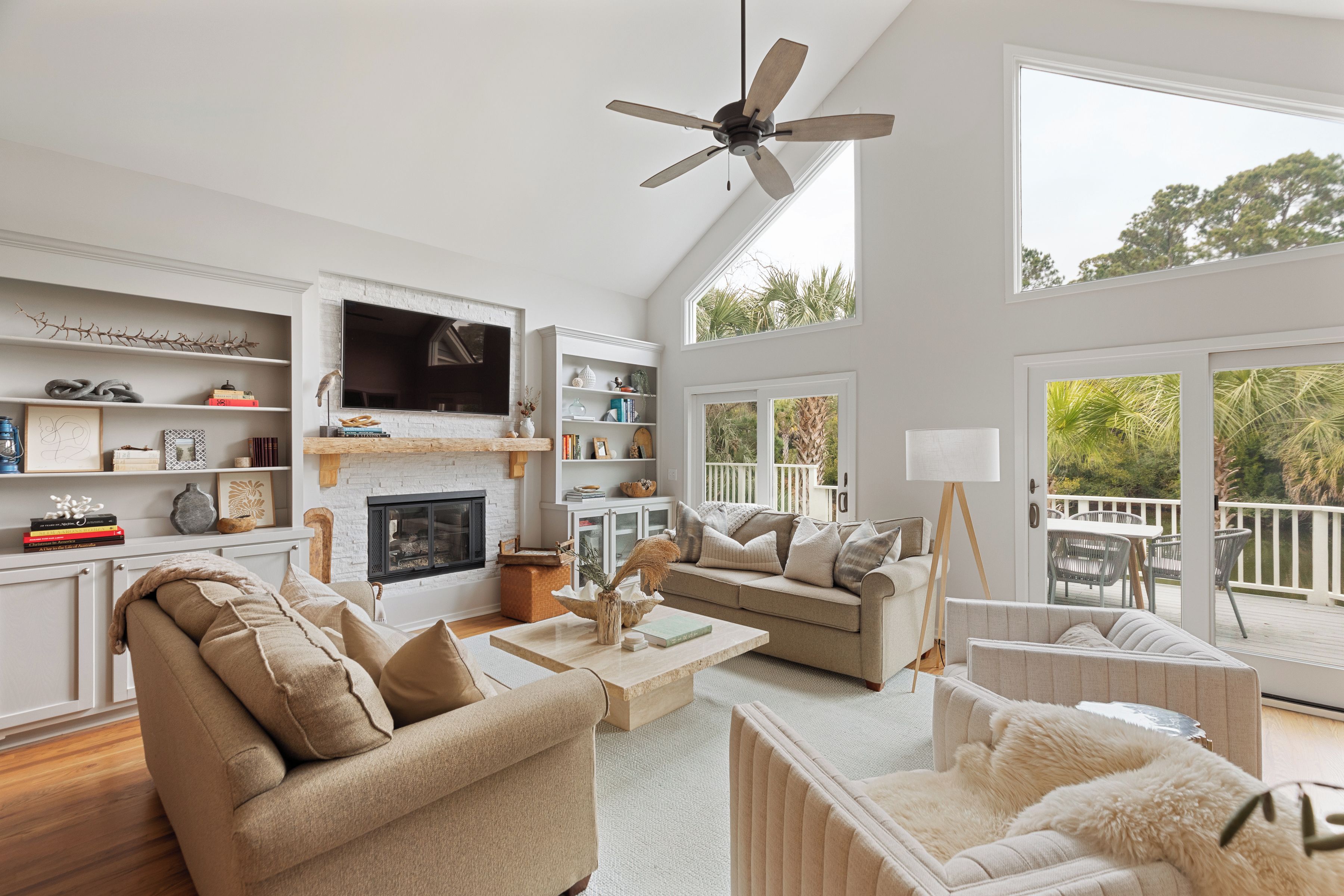A spacious living room with a fireplace, a large TV, and a balcony with outdoor furniture.