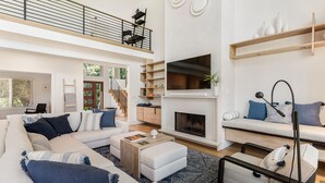 Amplia sala de estar con techo alto, chimenea, un conjunto de sofás y un comedor.