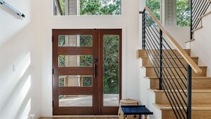 Un interior moderno con una escalera de madera, un espejo grande y un tapete redondo tejido.
