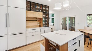 Una cocina moderna con armarios blancos, detalles de madera y una isla central.