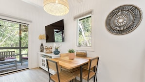 A dining area with a wooden table and chairs, a large mirror, and a decorative wall piece. - New reno, Boho-style "treehouse" at the beach! (Kiawah Island)