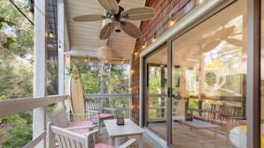 A covered outdoor patio with white furniture, a ceiling fan, and string lights. - New reno, Boho-style "treehouse" at the beach! (Kiawah Island)