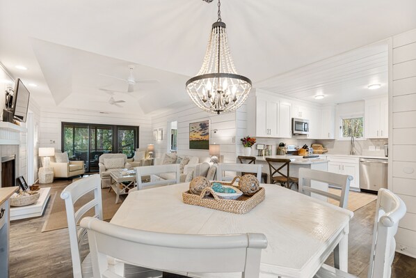 A spacious kitchen with white cabinetry, a dining area with a white table and chairs, and a chandelier.