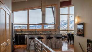 A kitchen with large windows, a bar area, and a view of mountains.