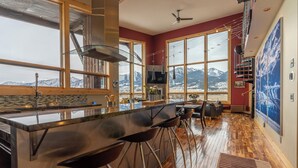 A modern kitchen with large windows, a bar area, and a view of mountains.
