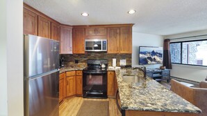 A modern kitchen with wooden cabinets, stainless steel appliances, a granite countertop, and a window with a mountain view. - Breckenridge Condo Only a Short Walk to Lifts & Shops w/ 2 Private Balconies! (Breckenridge)