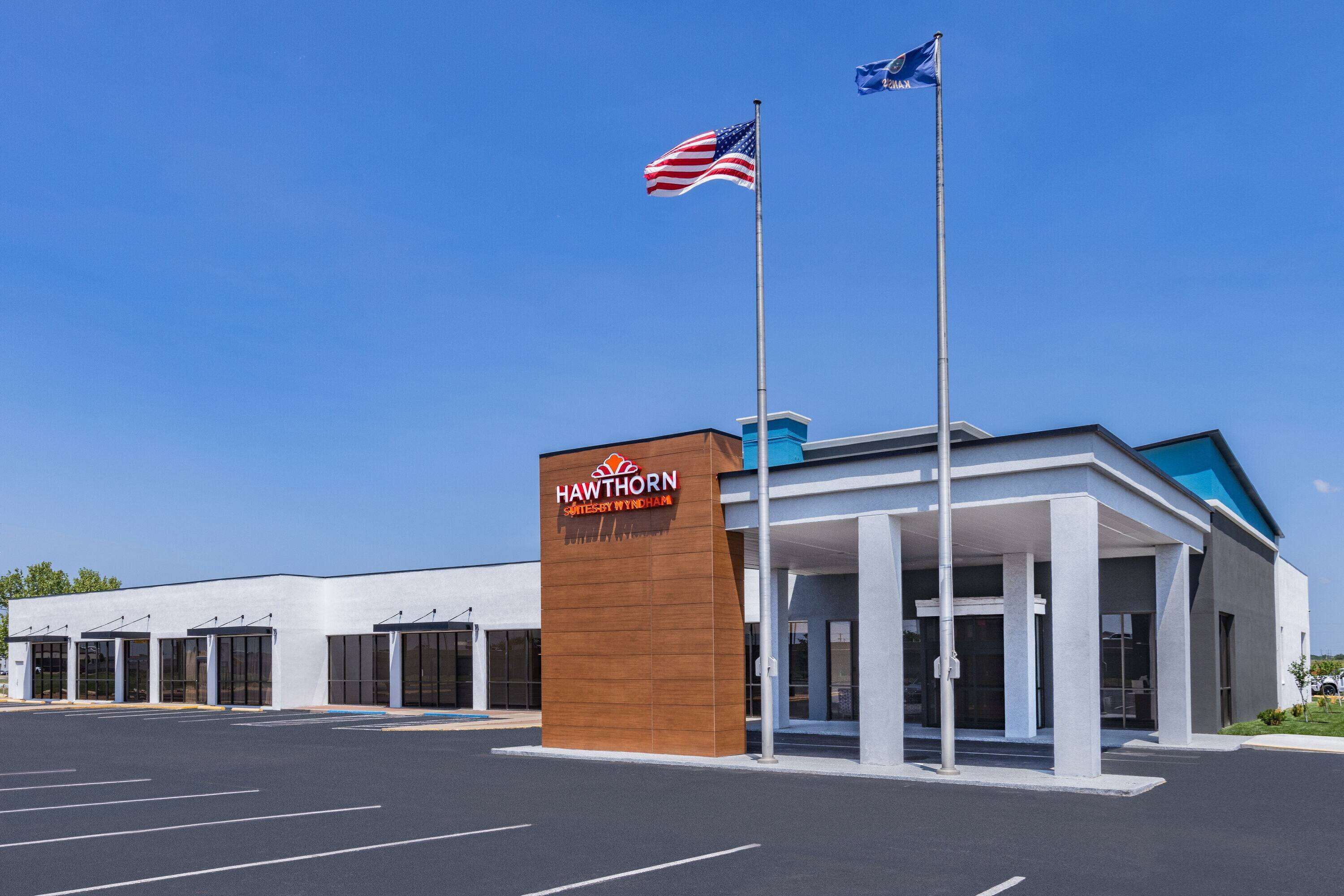 A Hawthorn Suites by Wyndham hotel with a modern design, featuring a prominent entrance and two flags.
