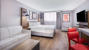 Een moderne hotelkamer met een bed, een bank, een salontafel, een televisie en een bureau.