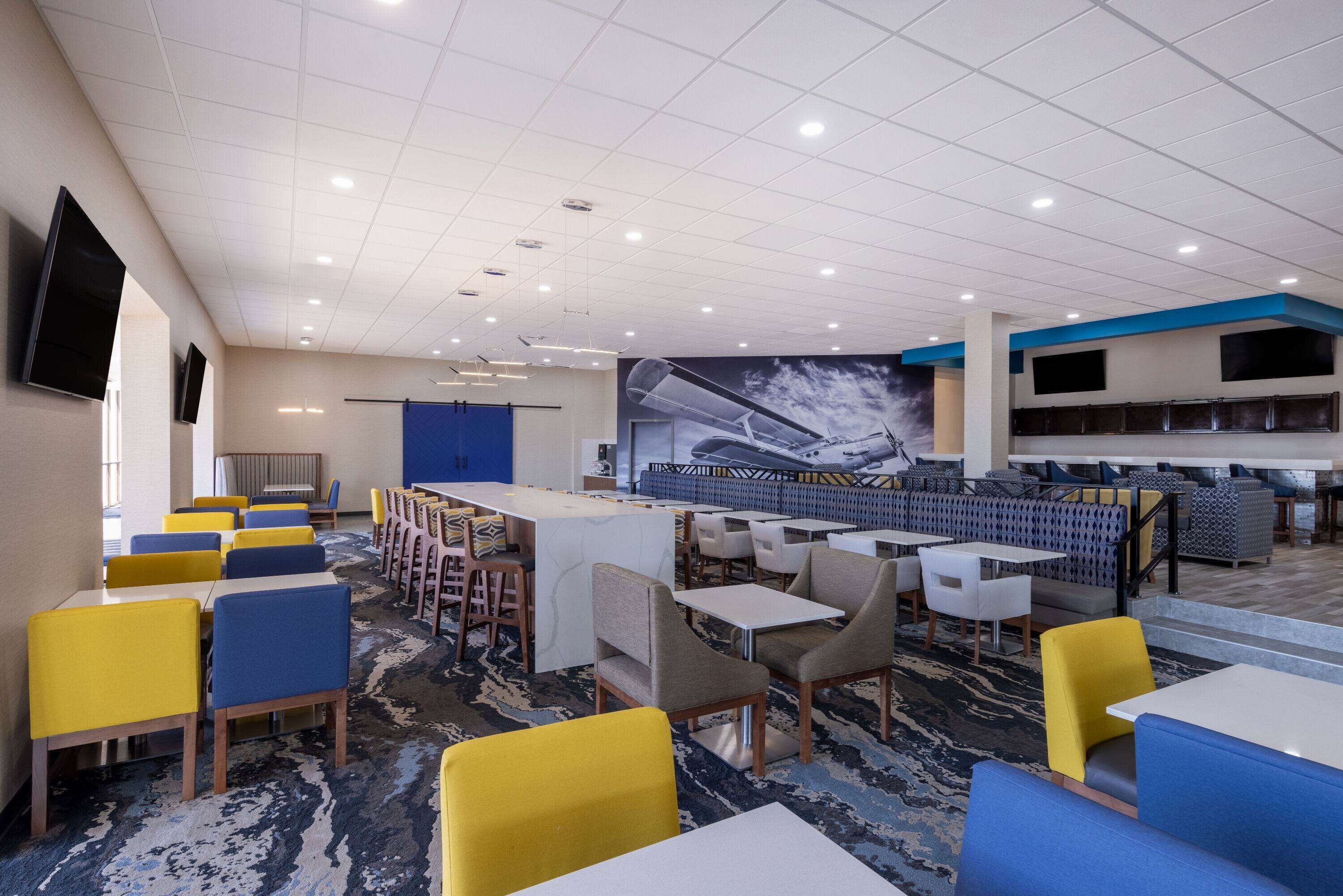 Una hall d'albergo con diverse zone salotto, un bar e un grande murale.