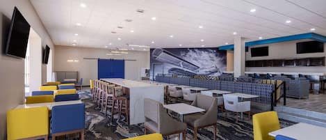 Una hall d'albergo con diverse zone salotto, un bar e un grande murale.